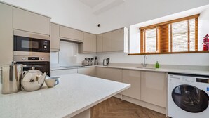 Una cocina moderna con horno empotrado, microondas y lavadora.