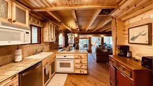 A wooden cabin interior with a kitchen, dining area, and living room.