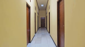 A long, narrow hallway with yellow walls and wooden doors on both sides.