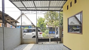 A covered outdoor area with a tiled floor, a metal gate, and a yellow wall.