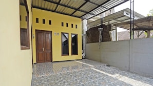 A building with a yellow exterior, a tiled patio, and a metal roof structure.