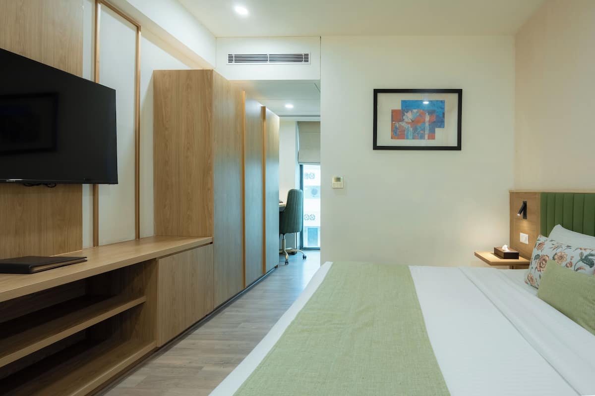 A hotel room with a bed, a TV, a desk, and a chair.