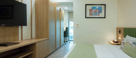 A hotel room with a bed, a TV, a desk, and a chair.
