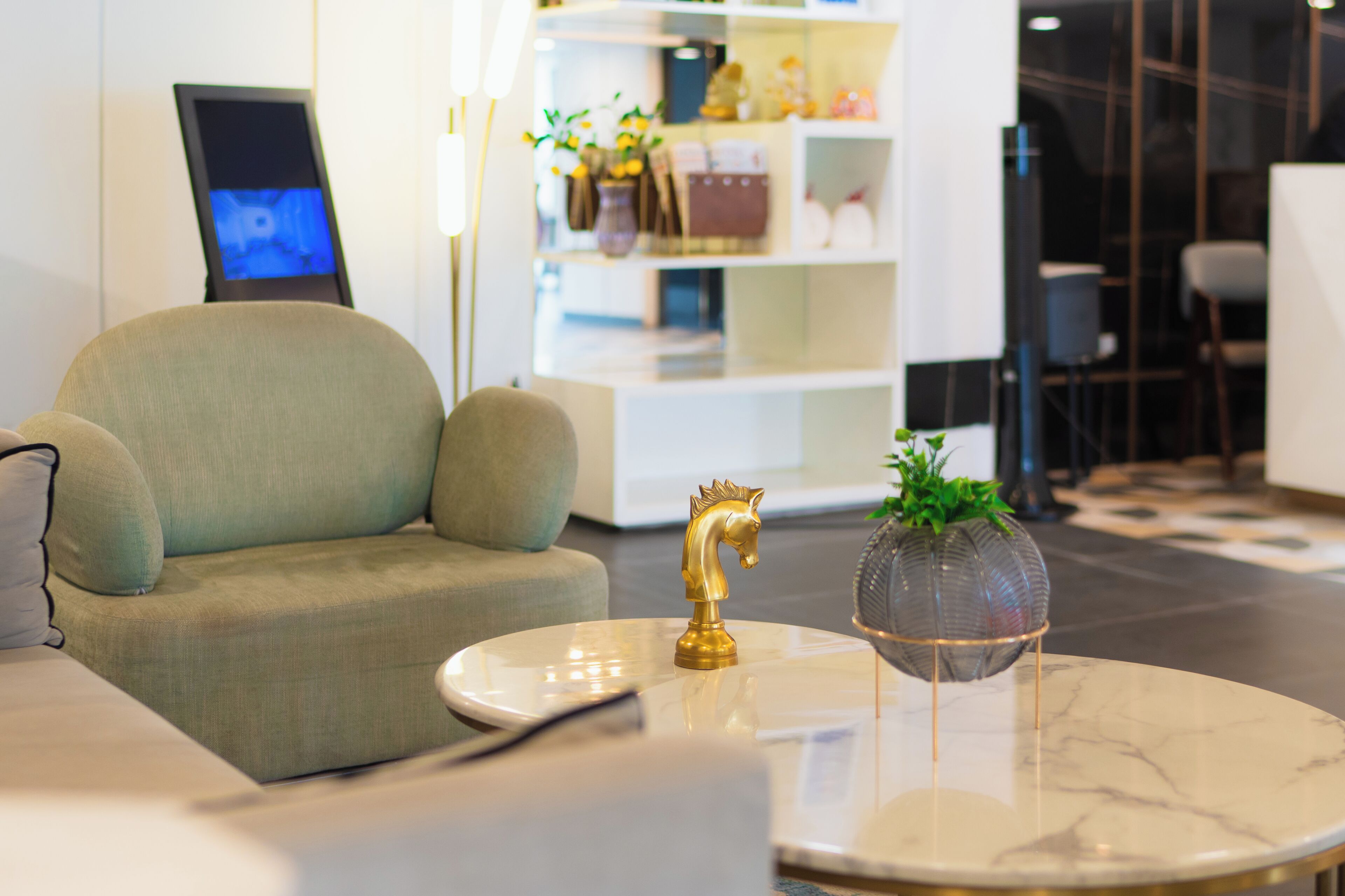 A modern interior with a sofa, a round table with a decorative item, and a bookshelf with various objects.