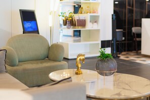 A modern interior with a sofa, a round table with a decorative item, and a bookshelf with various objects.