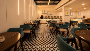 A restaurant with a geometric patterned floor, teal chairs, and a bar area with framed pictures. - Hotel Limon Sector 29, Gurgaon (Gurugram)