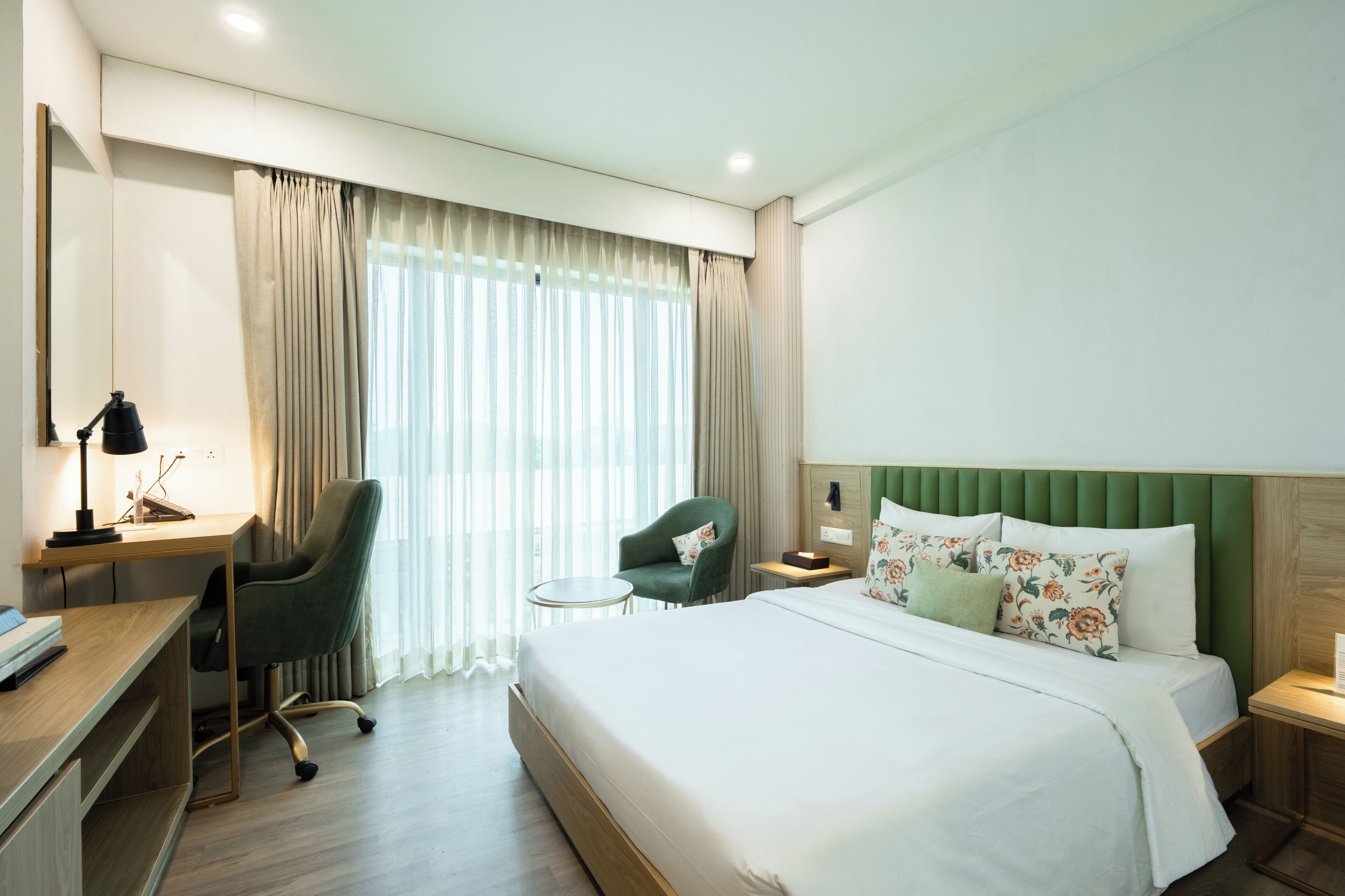 Een hotelkamer met een bed, bureau, stoel en een klein tafeltje.