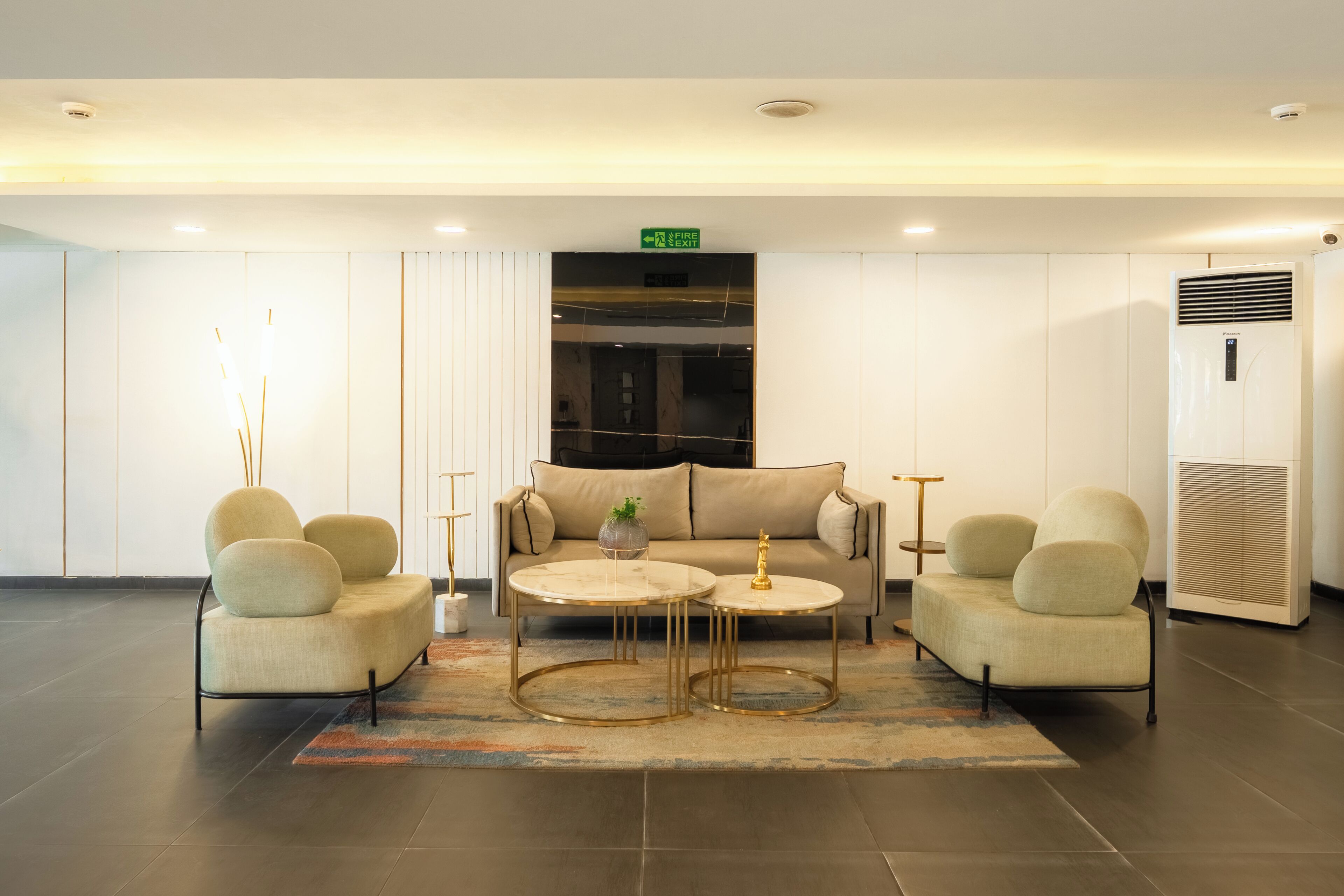 A modern lobby with a sofa, two armchairs, a coffee table, and a rug.