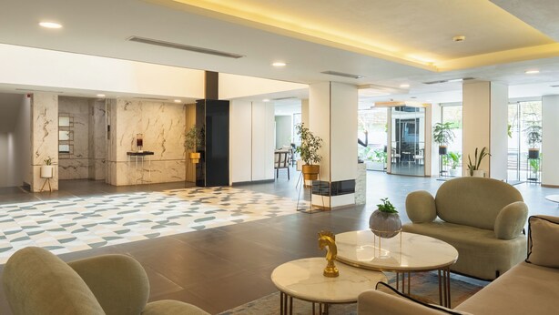 A spacious lobby with a marble reception desk, comfortable seating, and large windows. - Hotel Limon Sector 29, Gurgaon (Gurugram)