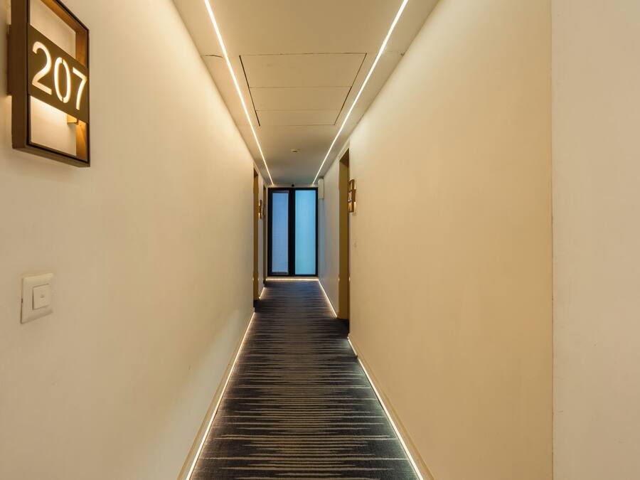 A hallway with a carpeted floor, a wall-mounted sign with the number 207, and a door at the end.