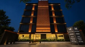 A modern hotel with a prominent vertical sign, a glass entrance, and a signboard listing amenities like rooms, residences, banquet, and sky lounge. - Hotel Limon Sector 29, Gurgaon (Gurugram)