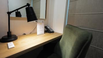 A desk with a lamp, a telephone, and a sign.