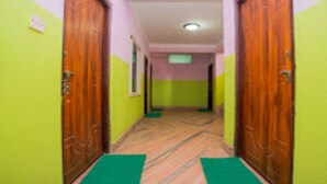 Un pasillo con puertas de madera y felpudos verdes en el suelo.