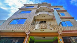 Un edificio de varios pisos con fachada decorativa, ventanas amplias y una entrada central con balcón.
