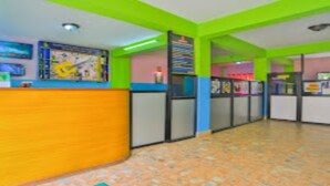Un interior de colores vivos con una recepción, un mural y un suelo de baldosas.