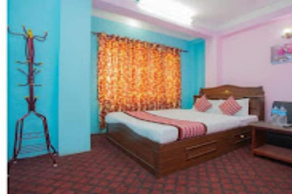 A bedroom with a bed, a wooden headboard, a bedside table, and a wall-mounted TV.