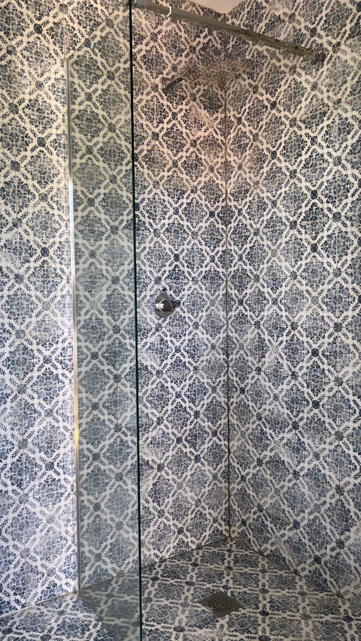 A bathroom with patterned tiles and a glass shower enclosure.