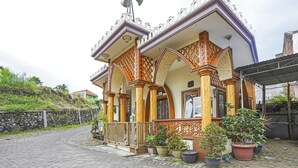 A traditional building with ornate wooden pillars and a balcony with potted plants. - Hotel O Lancar Homestay Syariah (Batu)