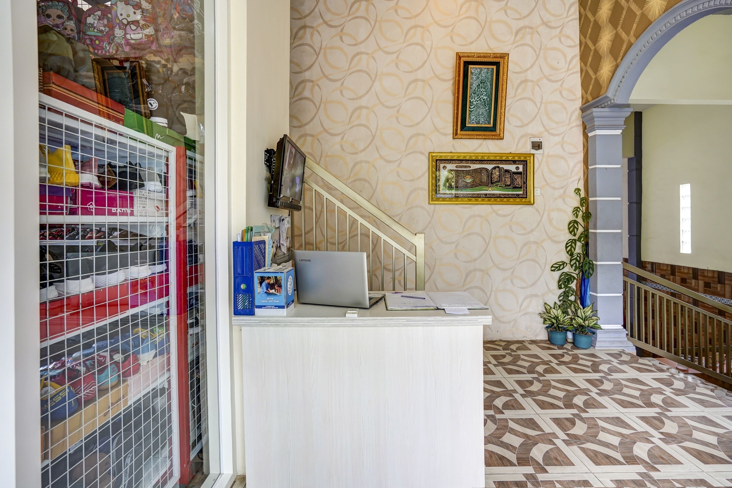 A reception desk with a laptop, papers, and a framed picture on the wall.