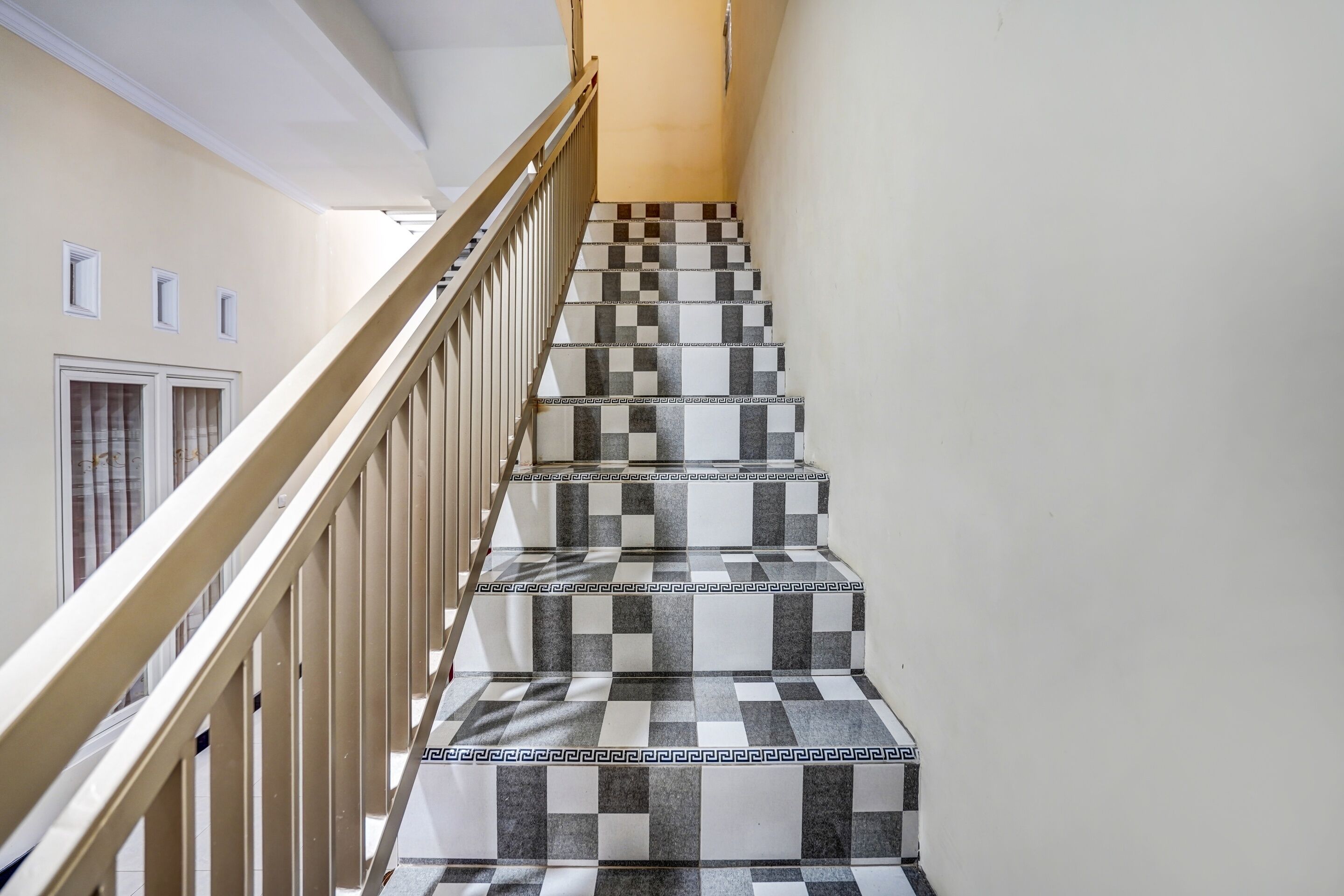 A staircase with a checkered tile pattern and a wooden handrail.