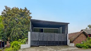 A single-story building with a metal roof and a large garage door. - OYO Life  91947 Kost Barokah Syariah (Mojokerto)