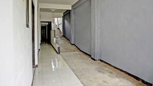 A hallway with a tiled floor, a staircase, and a grey wall. - OYO Life  91947 Kost Barokah Syariah (Mojokerto)