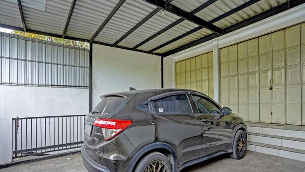A black SUV parked inside a covered garage with a tiled floor and metal railings. - OYO Life  91947 Kost Barokah Syariah (Mojokerto)