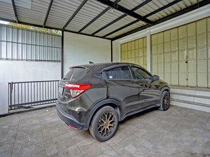 A black SUV parked inside a covered garage with a tiled floor and metal railings. - OYO Life  91947 Kost Barokah Syariah (Mojokerto)