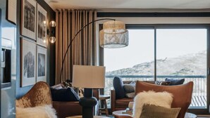 Una sala de estar moderna con un ventanal grande, un sofá, un sillón y una lámpara.