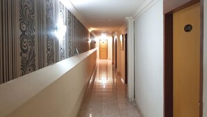 A hotel corridor with patterned wallpaper, a light-colored floor, and a door with a number plaque. - Hotel O Istana (Makassar)