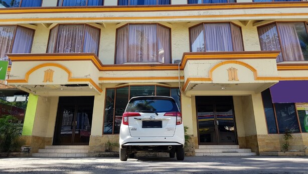 A multi-story hotel with a white car parked in front. - Hotel O Istana (Makassar)