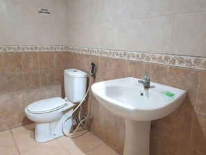 Une salle de bain avec des toilettes, un lavabo et des murs carrelés.