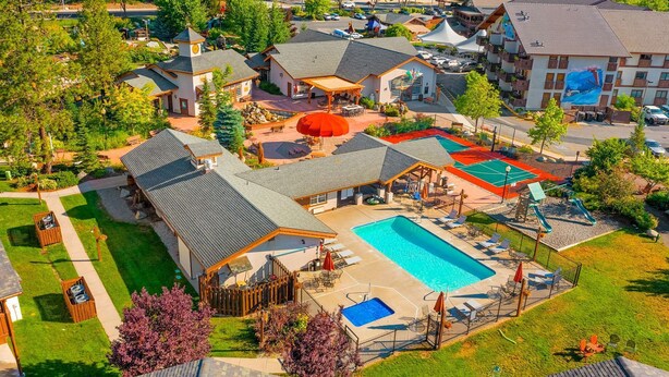A resort with a large swimming pool, outdoor seating areas, and a covered patio.