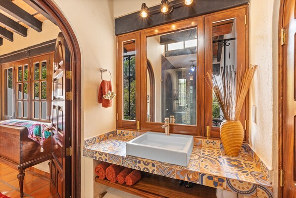A bathroom with a large mirror, a sink, and a wooden vanity. - Beautiful Condo at Amapas with Tropical View 2BD Condo for rent in Conchas China (Puerto Vallarta)