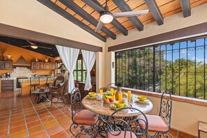 A dining area with a round table, chairs, and a view through a window with metal bars. - Beautiful Condo at Amapas with Tropical View 2BD Condo for rent in Conchas China (Puerto Vallarta)