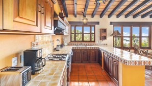 Una cocina con armarios de madera, salpicadero de azulejos, estufa y cafetera.