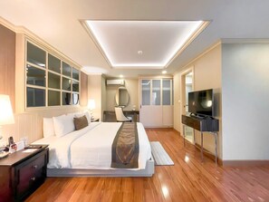 Una habitación de hotel moderna con una cama grande, un escritorio, un televisor y un armario.