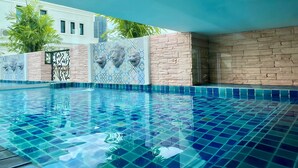 Una piscina con mosaicos azules, rodeada de muros de piedra y decoradas cabezas de león.