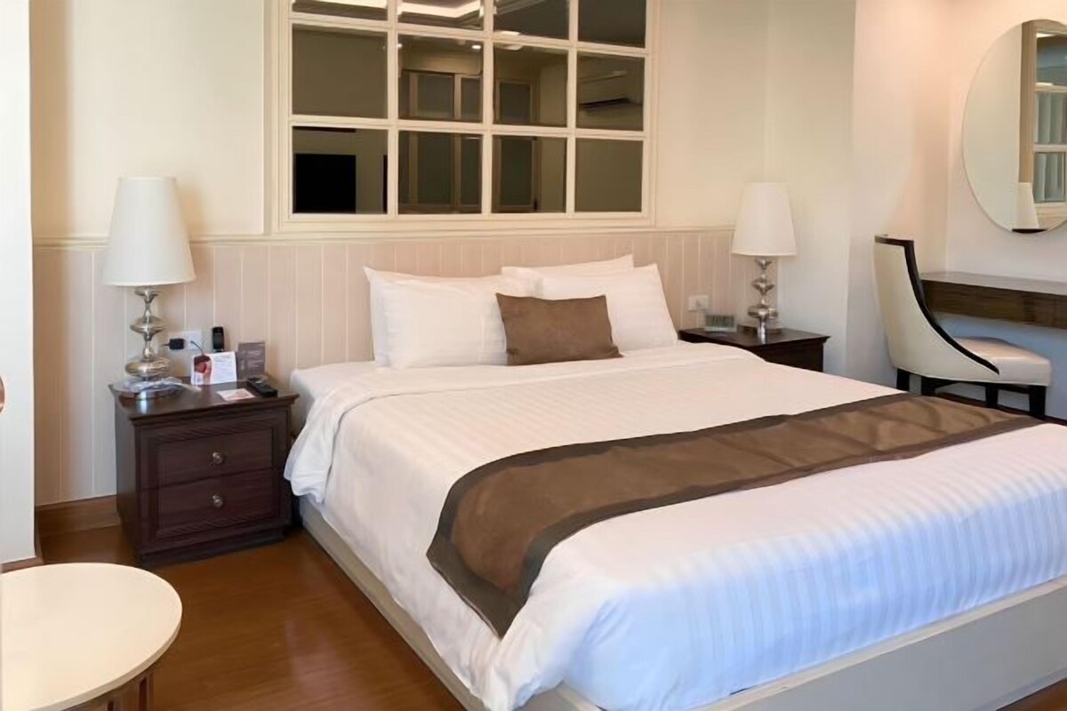 Habitación de hotel impecable con una cama grande, mesitas de noche, una mesa redonda y un espejo.