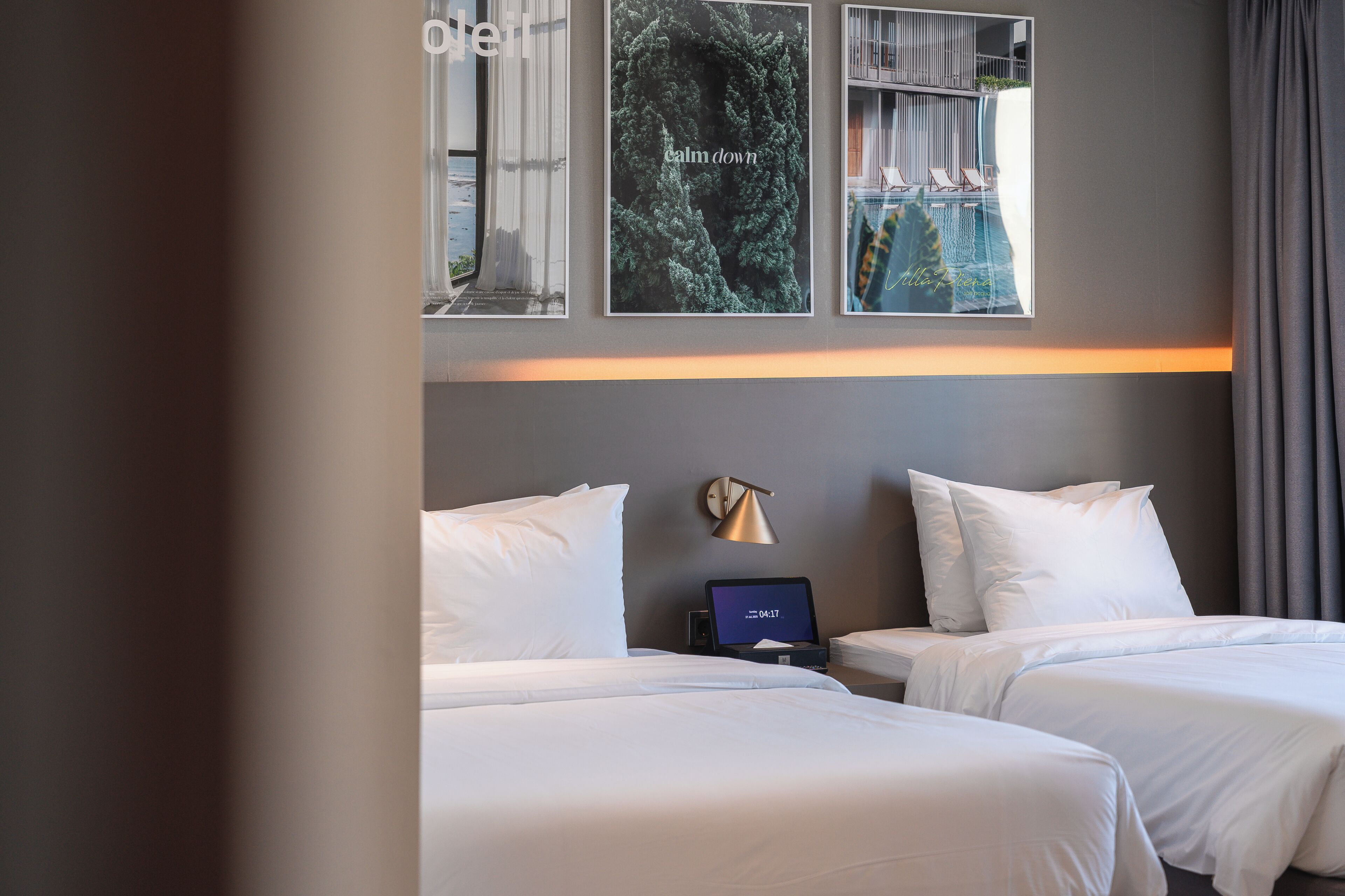 Habitación de hotel con dos camas, una mesita de noche con un reloj y una decoración en la pared.