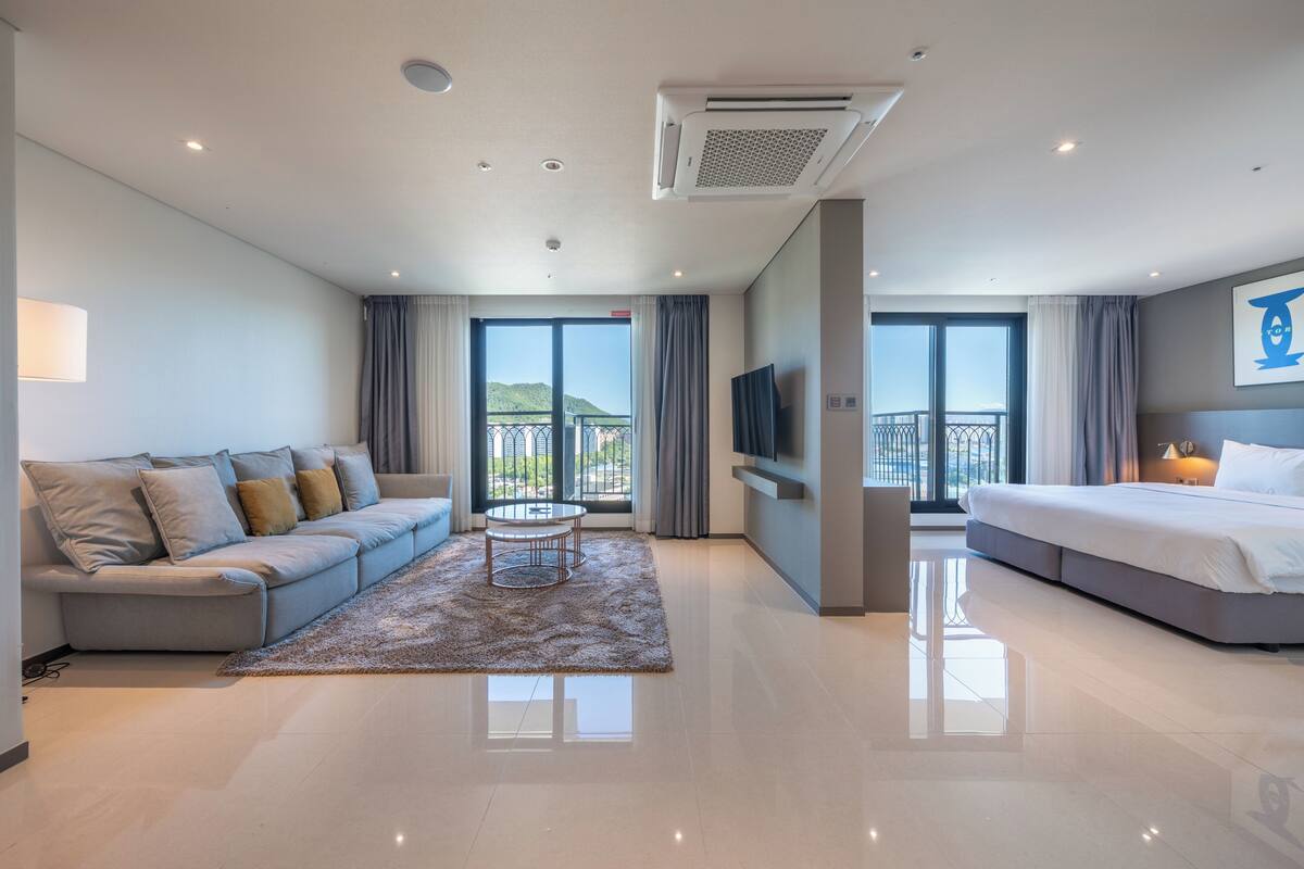 Een moderne hotelkamer met een bank, een bed, een televisie en een balkon met uitzicht.