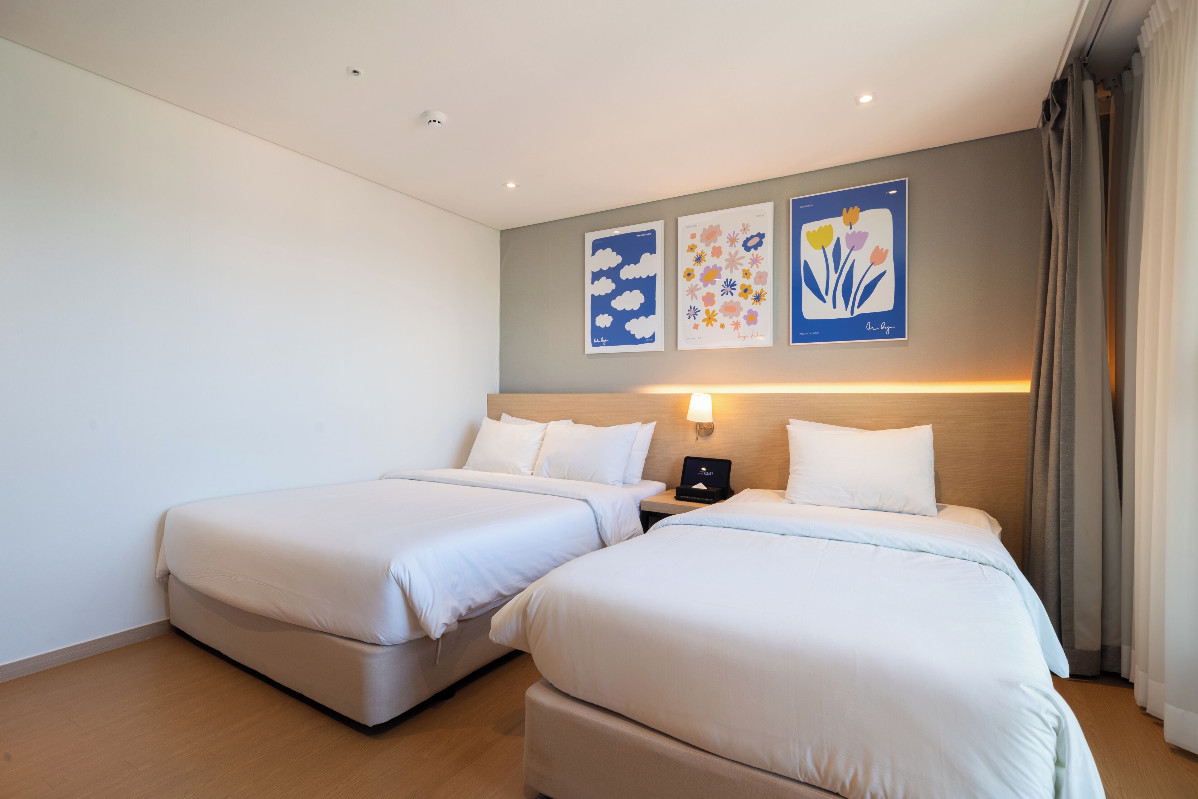 Ein Hotelzimmer mit zwei Betten, einem Nachttisch und Wandbildern.