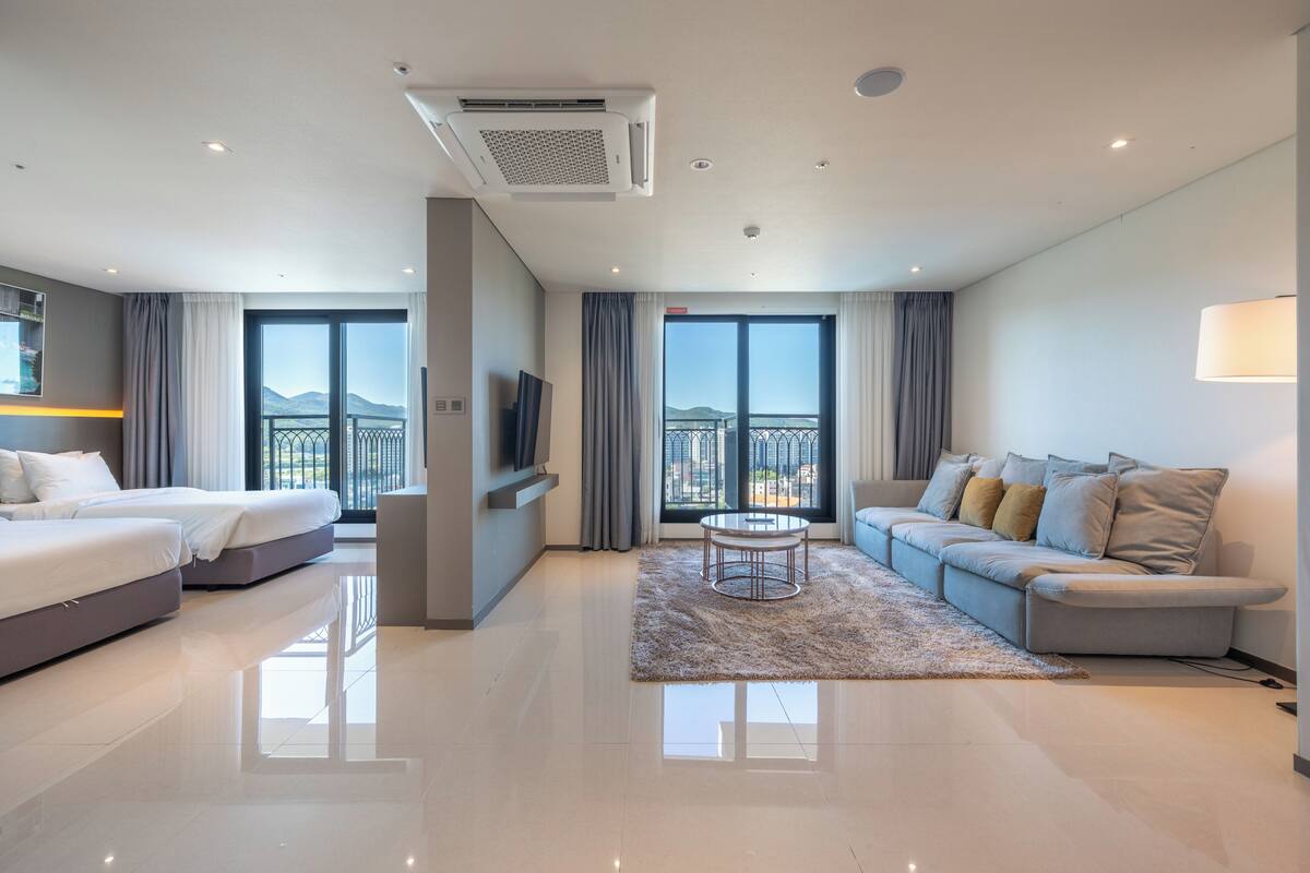 Een moderne hotelkamer met een bed, een bank, een televisie en een balkon met uitzicht.