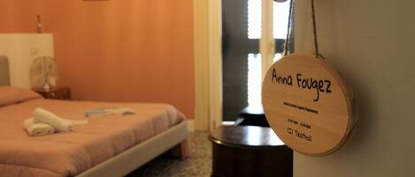 A hotel room with a bed, a bedside table, and a wall-mounted lamp.