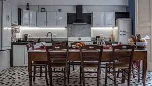Cozinha moderna com armários brancos, bancada de mármore e área de jantar com mesa posta para quatro pessoas.