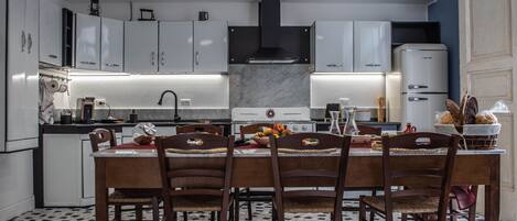A modern kitchen with white cabinets, a marble countertop, and a dining area with a table set for four.