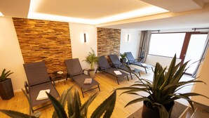 A modern lounge area with wooden wall panels, multiple lounge chairs, a potted plant, and a large window providing natural light. - Q, stable, chalet I whole house I ski I sauna (Brilon)