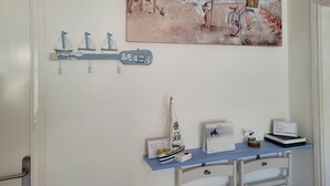 A wall with a calendar, a small sailboat, and a painting of a woman by the sea. - OMEGA 4 2-C (Estartit)