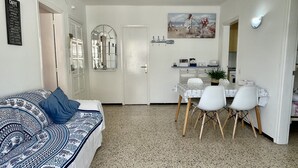 A compact living space with a dining area, a sofa with patterned upholstery, and a wall-mounted mirror. - OMEGA 4 2-C (Estartit)