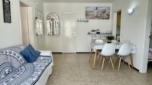 Een knus woongedeelte met een eethoek, een bank met een gestreept zitvlak en een spiegel aan de muur.